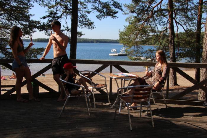 Sääkjärven kahvion terassilla syö jäätelöä nuoripari sekä äiti ja poika. Taustalla järvinäkymä.