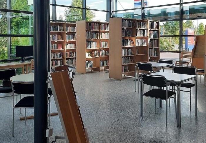 Pääkirjaston palvelupisteen sali. Kirjahyllyjä, tuoleja ja pöytiä.