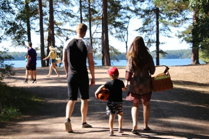 Kaksi aikuista ja lapsi kävelevät kohti Sääksin uimarantaa kädessään eväskori.