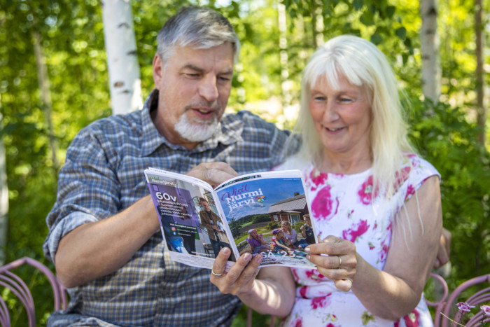 Iäkäs pariskunta lukee puutarhatuolilla Nurmijärven esitettä.