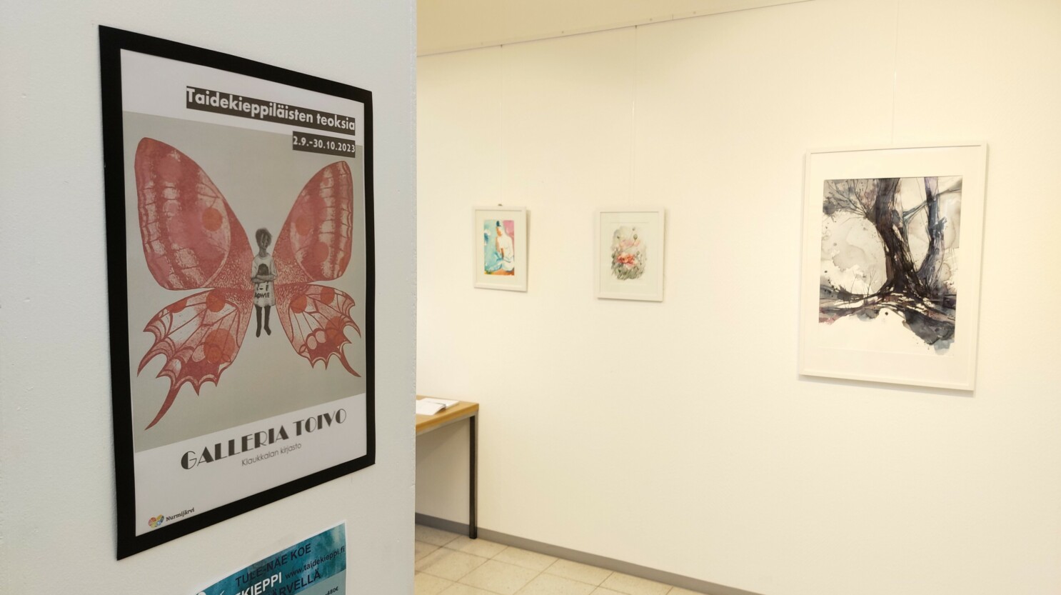 Juliste Taidekieppiläisten näyttelystä. Taustalla kolme maalausta.